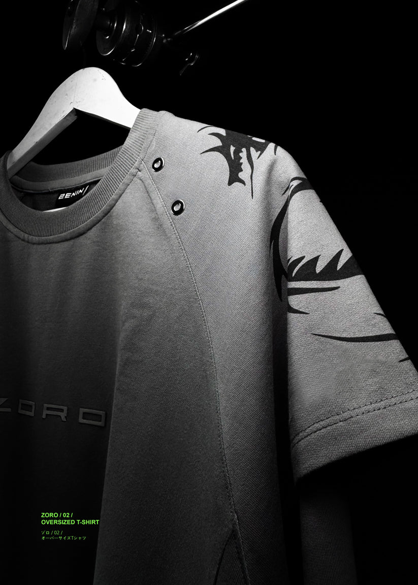 Gray t-shirt with black leaf patterns on a hanger against a dark background