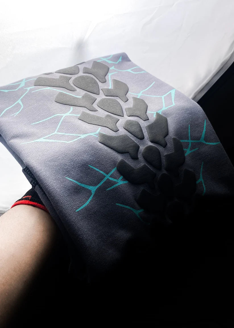 Person wearing a dark gray sleeve with geometric patterns on a white background